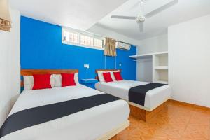 two beds in a room with a blue wall at Capital O Hotel El Mejicano, Acapulco in Acapulco +52 photos