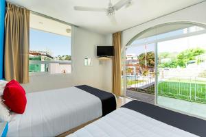 a hotel room with two beds and a large window at Capital O Hotel El Mejicano, Acapulco in Acapulco