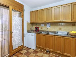 a kitchen with wooden cabinets and a sink and a dishwasher at Villa Palmera I by Interhome in L'Ametlla de Mar