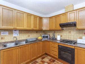 a kitchen with wooden cabinets and a sink at Villa Palmera I by Interhome in L'Ametlla de Mar +17 photos