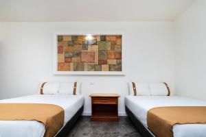 two beds in a room with a painting on the wall at Capital O Hotel Joyma Suites, San Luis in San Luis Potosí