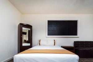 a bedroom with a bed and a black chair at Capital O Hotel Joyma Suites, San Luis in San Luis Potosí +30 photos