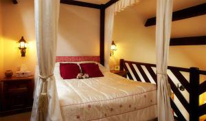 ein Schlafzimmer mit einem Himmelbett und roten Kissen in der Unterkunft Langford Executive Apartments in Bristol