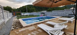 a swimming pool with white chairs and an umbrella at Holiday Home in Vǝndam