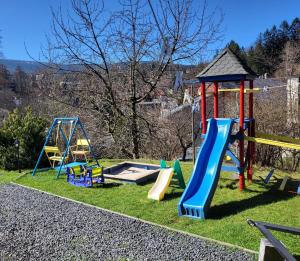 un parque infantil con dos columpios y un tobogán en Pensjonat Jeleni Róg, en Szklarska Poręba