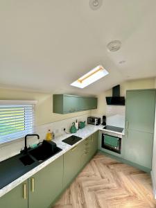 a kitchen with green cabinets and a sink at Luxury Coastal Cottage in Portsoy