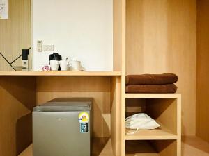 a small refrigerator under a shelf in a kitchen at The Cozy 77 in Bangkok