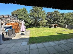 a patio with an umbrella and a grass yard at Ferienhaus Fresen Hus Humptrup in Humptrup