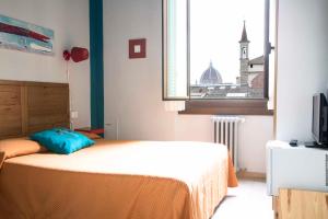 Un dormitorio con una cama y una ventana con una torre de reloj. en Hotel Panorama en Florencia