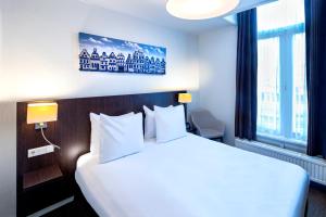 pokój hotelowy z dużym łóżkiem i białymi poduszkami w obiekcie Hotel Nes Amsterdam w Amsterdamie
