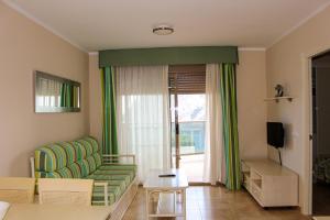 a living room with a green couch and a window at Apartamentos Esmeralda Suites Unitursa in Calpe