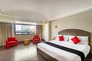 ein Hotelzimmer mit einem Bett und zwei roten Stühlen in der Unterkunft Capital O Andrade, Mexico City in Mexiko-Stadt