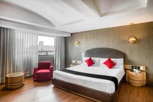 ein Hotelzimmer mit einem Bett und einem roten Stuhl in der Unterkunft Capital O Andrade, Mexico City in Mexiko-Stadt