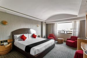 ein Hotelzimmer mit einem Bett und zwei roten Stühlen in der Unterkunft Capital O Andrade, Mexico City in Mexiko-Stadt
