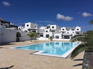 a swimming pool in front of a white house at Relájate en planta alta - Playa B in Playa Blanca