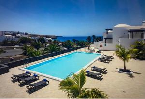 a swimming pool with lounge chairs and the ocean at Relájate en planta alta - Playa B in Playa Blanca