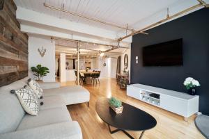 een woonkamer met een bank en een tv aan de muur bij Lion's Den // Spacious 1500 sqft (2 WC) - Downtown in Québec