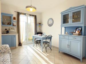 a kitchen with blue cabinets and a table and a clock at 250 mt dal mare - Relax e Posto Auto in Pietra Ligure