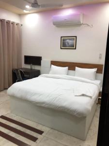a bedroom with a large white bed and a desk at Hotel Kings Night in Greater Noida