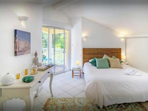 a white bedroom with a bed and a desk at Villa Samasti - OVO Network in Lacanau