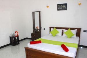 a bedroom with a bed with red and green pillows at Royal Breeze Resort Sigiriya in Sigiriya