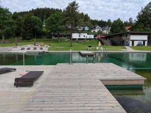 a bench sitting on a dock next to a lake at Ferienwohnungen Schönwald in Schonwald im Schwarzwald