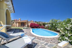 a backyard with a swimming pool and chairs and a house at Villa Azzurra in Stintino