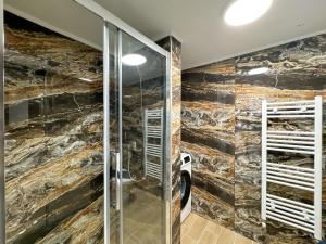a bathroom with a shower with a stone wall at Empire Apartment 4 in Néa Michanióna +18 photos