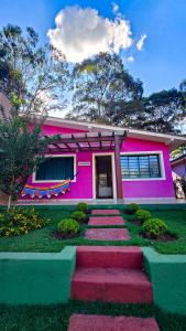 una casa rosa con gradini rossi davanti di Villa das Águas a Monte Alegre do Sul