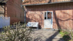 a brick house with a white door and a bench at Gemütliches Apartment im Grünen mit Kamin und Klöntür in Altenmedingen