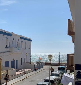 een straat met auto's geparkeerd naast de oceaan bij Apartamento Clavel in Chipiona