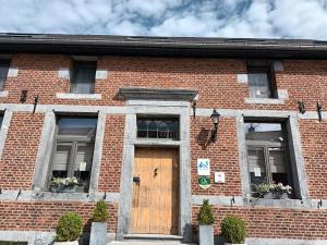 a brick building with a wooden door and windows at Le Relais De La Motte in Soignies