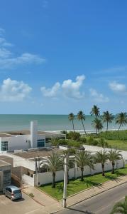 a view of a building with palm trees and the ocean at Apartamento em João Pessoa - Frente Pro Mar in João Pessoa