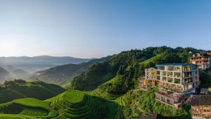 龙胜山水间的家民宿（龙脊梯田店）的田野旁山丘上的建筑物