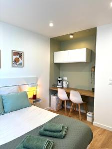 a bedroom with a bed and a table and a kitchen at Entre Nantes et aéroport - Arrivée autonome 24h sur 24h in La Montagne