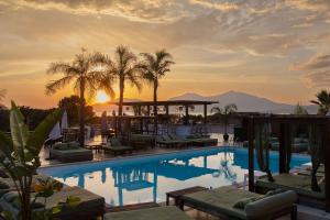 a resort pool with a gazebo and palm trees at Bella Vista Hôtel, Suites & Maisons in Porticcio