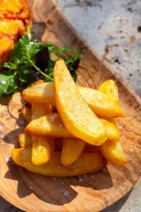 a pile of french fries on a wooden plate at Bella Vista Hôtel, Suites & Maisons in Porticcio