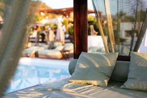 a bed with pillows sitting next to a swimming pool at Bella Vista Hôtel, Suites & Maisons in Porticcio