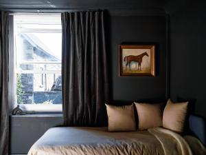 a bedroom with a bed and a window with a horse painting at Cambridge House in Windermere