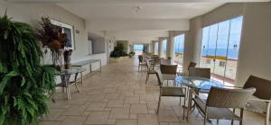 a dining room with tables and chairs and the ocean at COBAR0108 - Edifício Oceania in Salvador