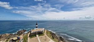 a lighthouse on a cliff in the ocean at COBAR0108 - Edifício Oceania in Salvador