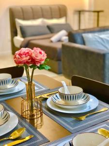 a table with plates and a vase with flowers on it at Shelisa's Cozy Retreat at Southplace Subang in Subang Jaya
