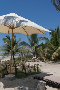 a tan umbrella on a beach with palm trees at Cabanas Adobe Frente Al Mar in Puerto Escondido