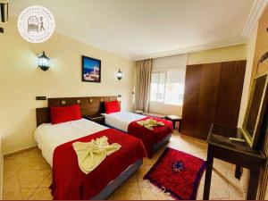a hotel room with two beds with red pillows at Hotel Merry in Agadir
