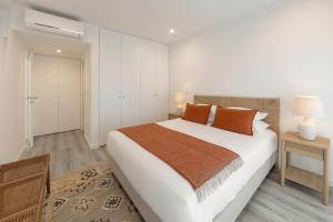 una camera da letto con un grande letto bianco con cuscini arancioni di Casa LukStian a Nazaré