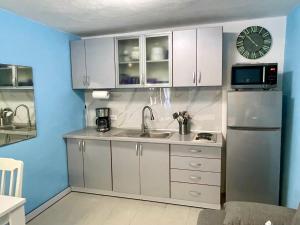 eine Küche mit weißen Schränken, einer Spüle und einem Kühlschrank in der Unterkunft Sutomore Panorama Studio in Sutomore