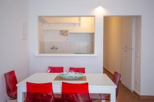 a dining room with a white table and red chairs at Capo Bianco Terrace - Helloelba in Portoferraio