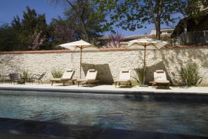 a group of chairs and umbrellas next to a pool at Villa Meridia in Nîmes