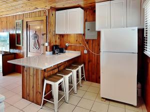 a kitchen with a white refrigerator and a counter with stools at Sea Glass Suites 3 in Topsail Beach