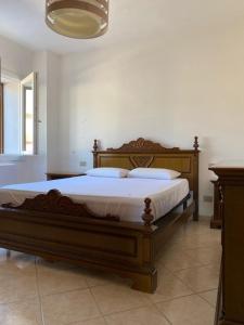 Un dormitorio con una gran cama de madera con sábanas blancas. en Filigheddu12, en Sassari